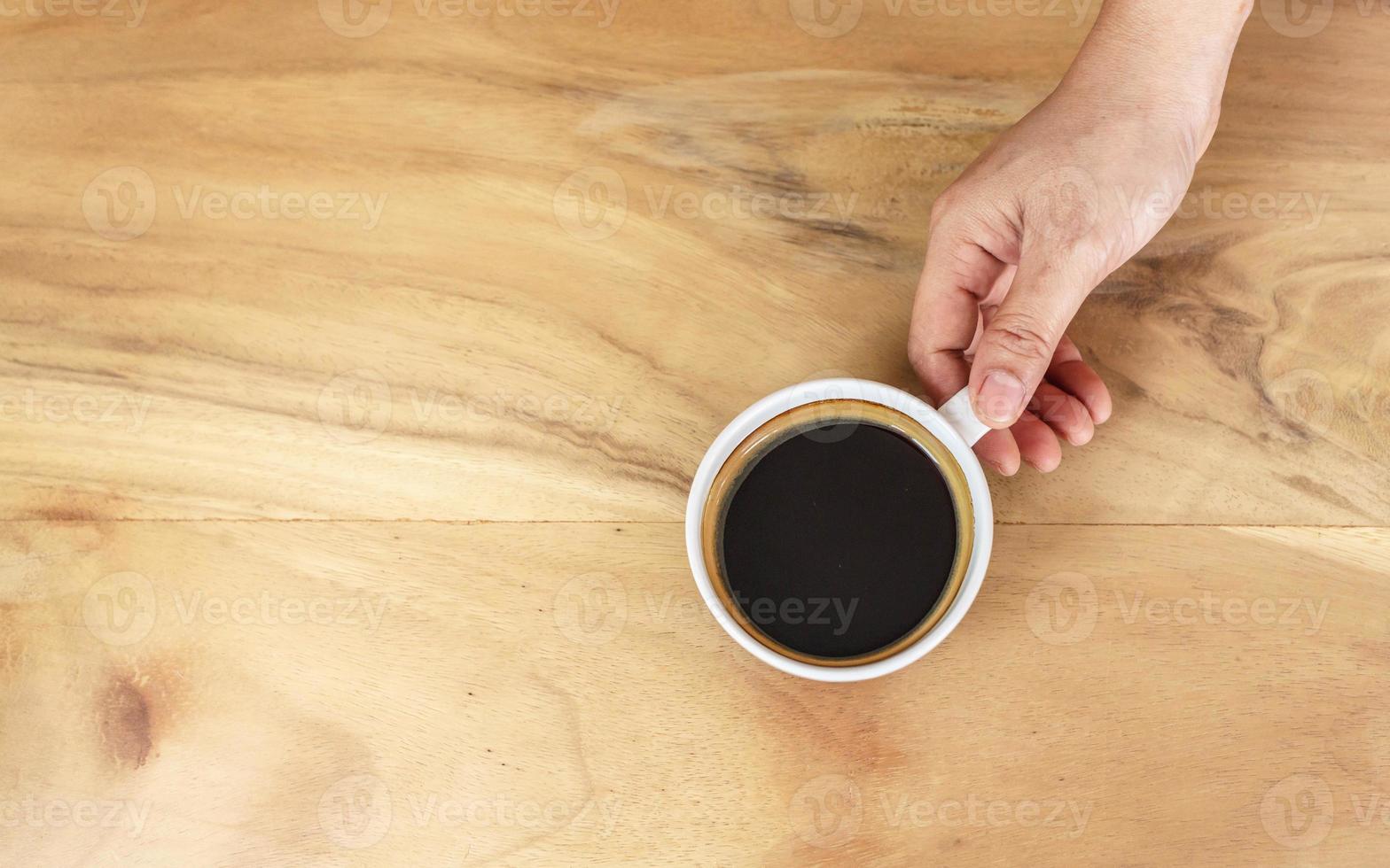 black coffee cup in hand on wooden table. photo