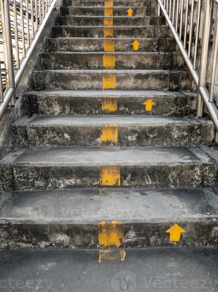 The concrete staircase with the yellow arrow symbol of the overpass in the city. photo