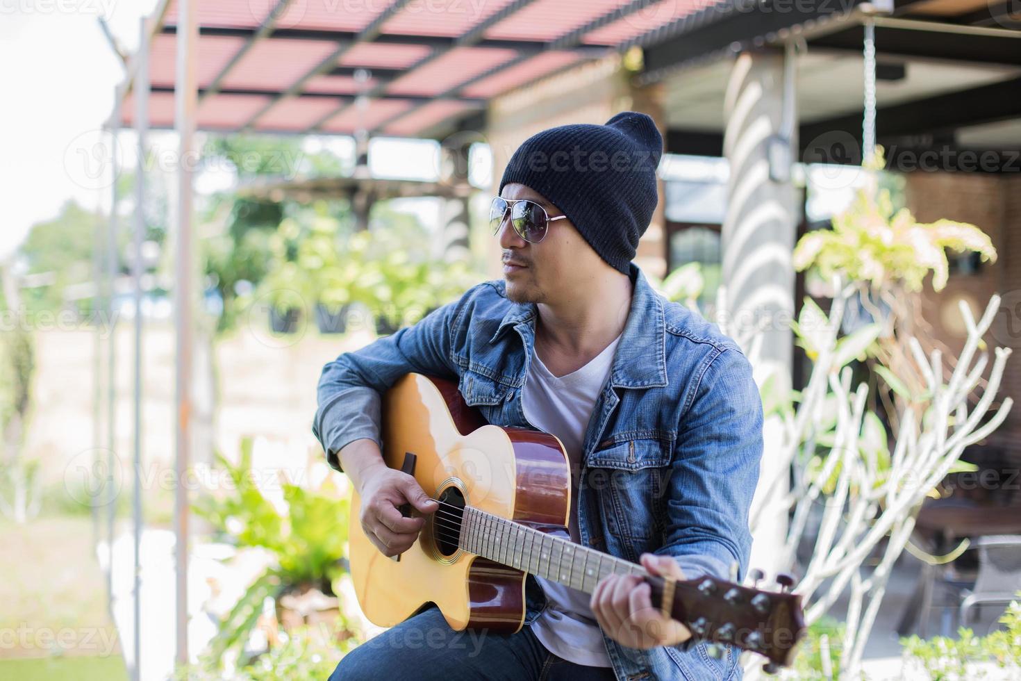 Young hipster man playing guitar to relaxing on his holiday, enjoy with natural and fresh air. photo