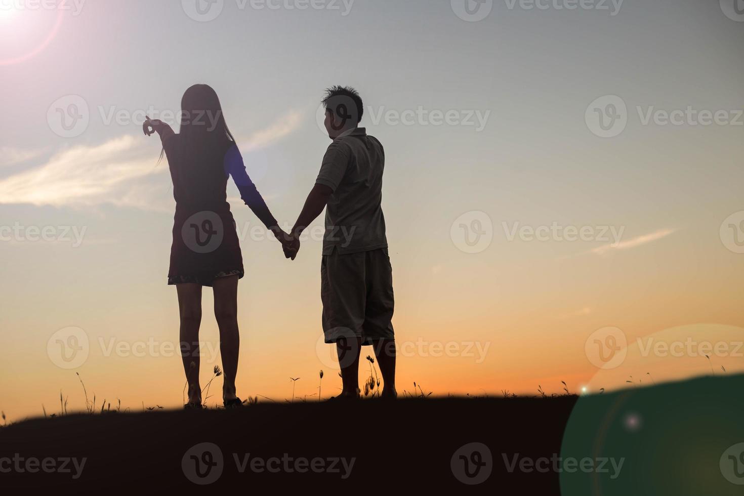 silhouette of a man and woman holding hands with each other, walking together. photo