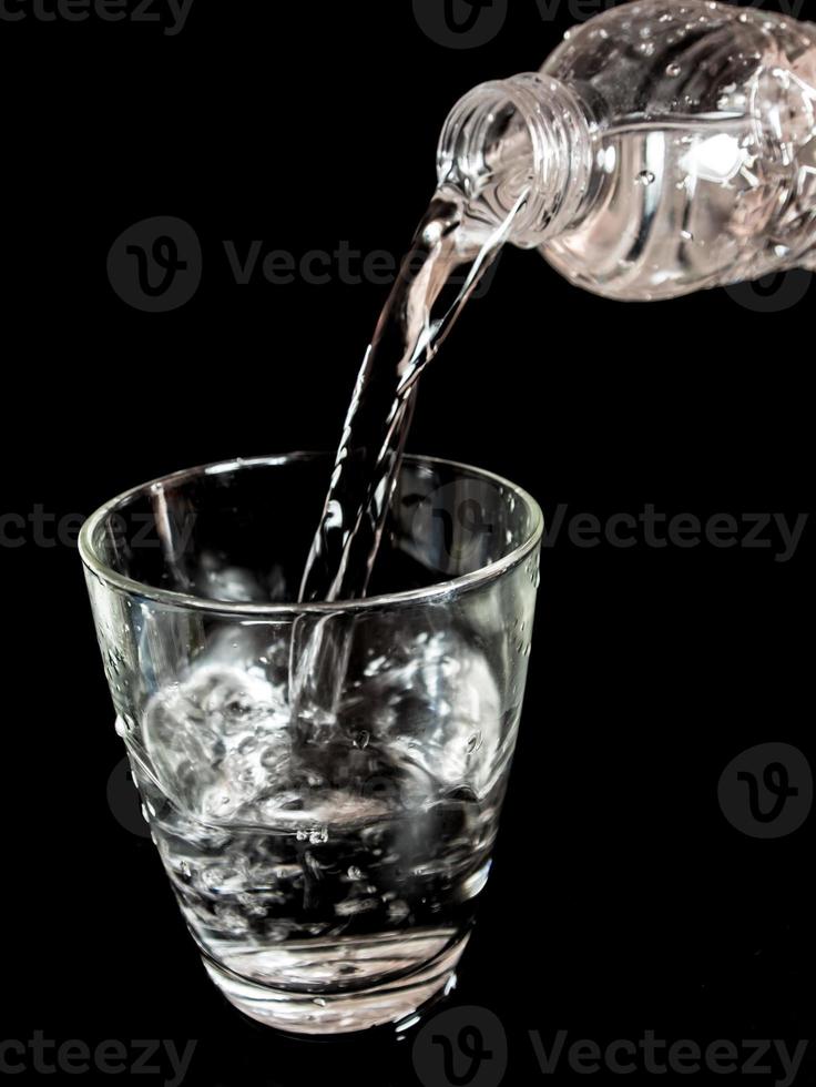 Pour water from the bottle into the glass photo