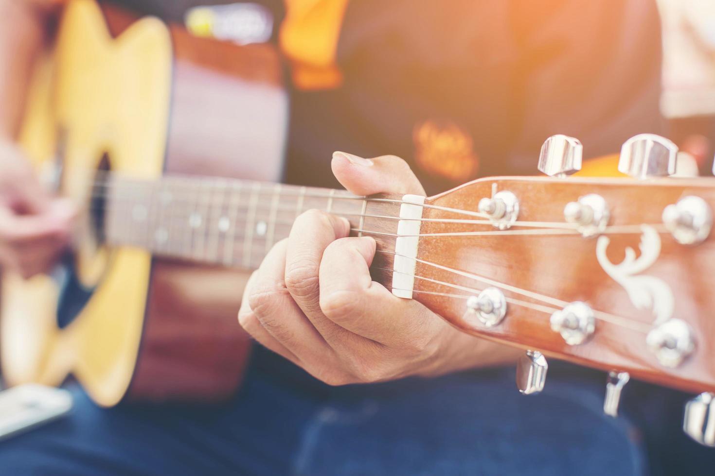 Cerca de la mano del hombre tocando la guitarra foto