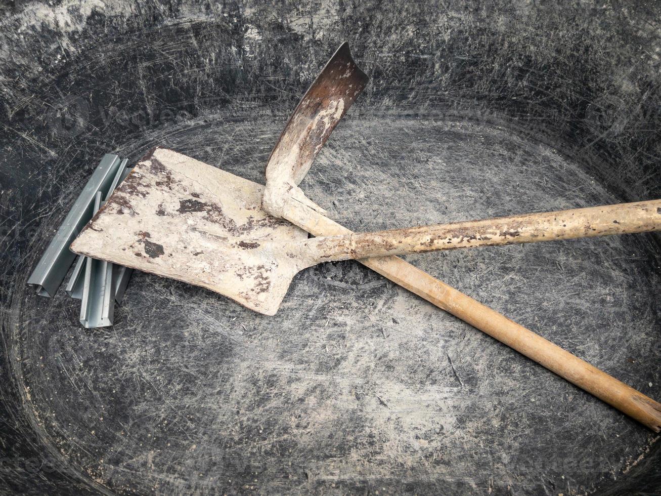 The old plastic bucket with the hoe and shovel for mixing the cement mortar. photo