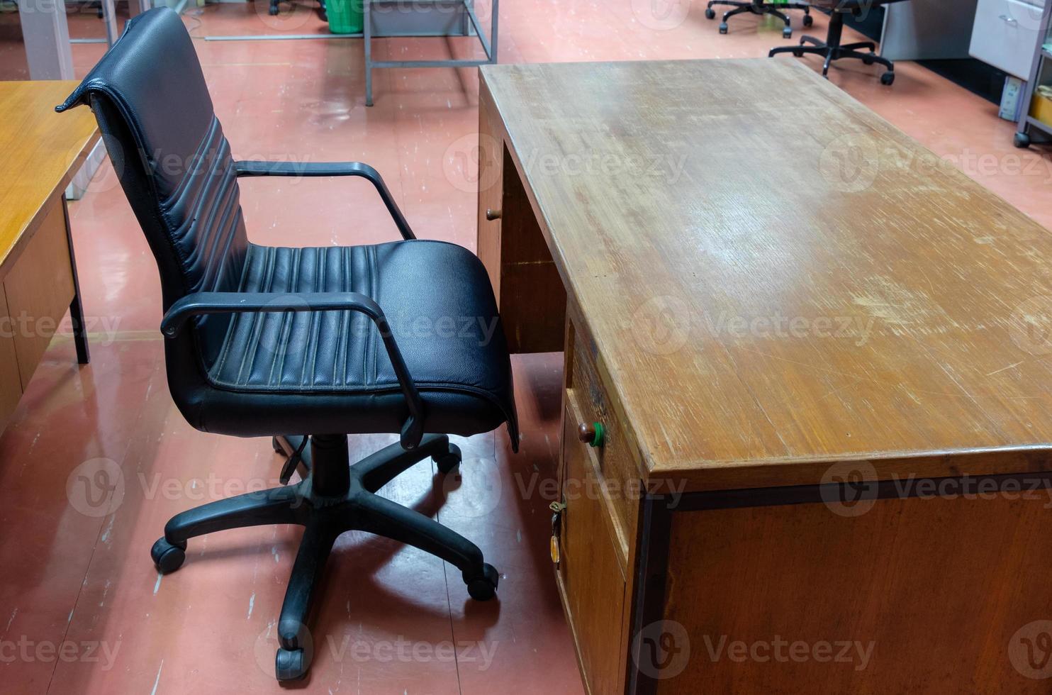 el sillón de cuero negro cerca de la vieja mesa de madera en la oficina local. foto