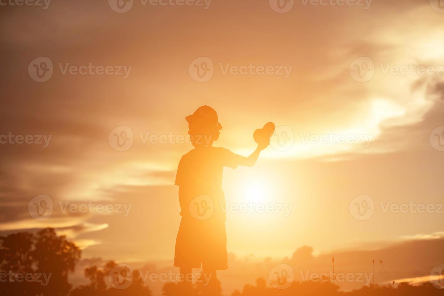 silueta de niño, momentos de alegría del niño. en la puesta de sol de la naturaleza foto