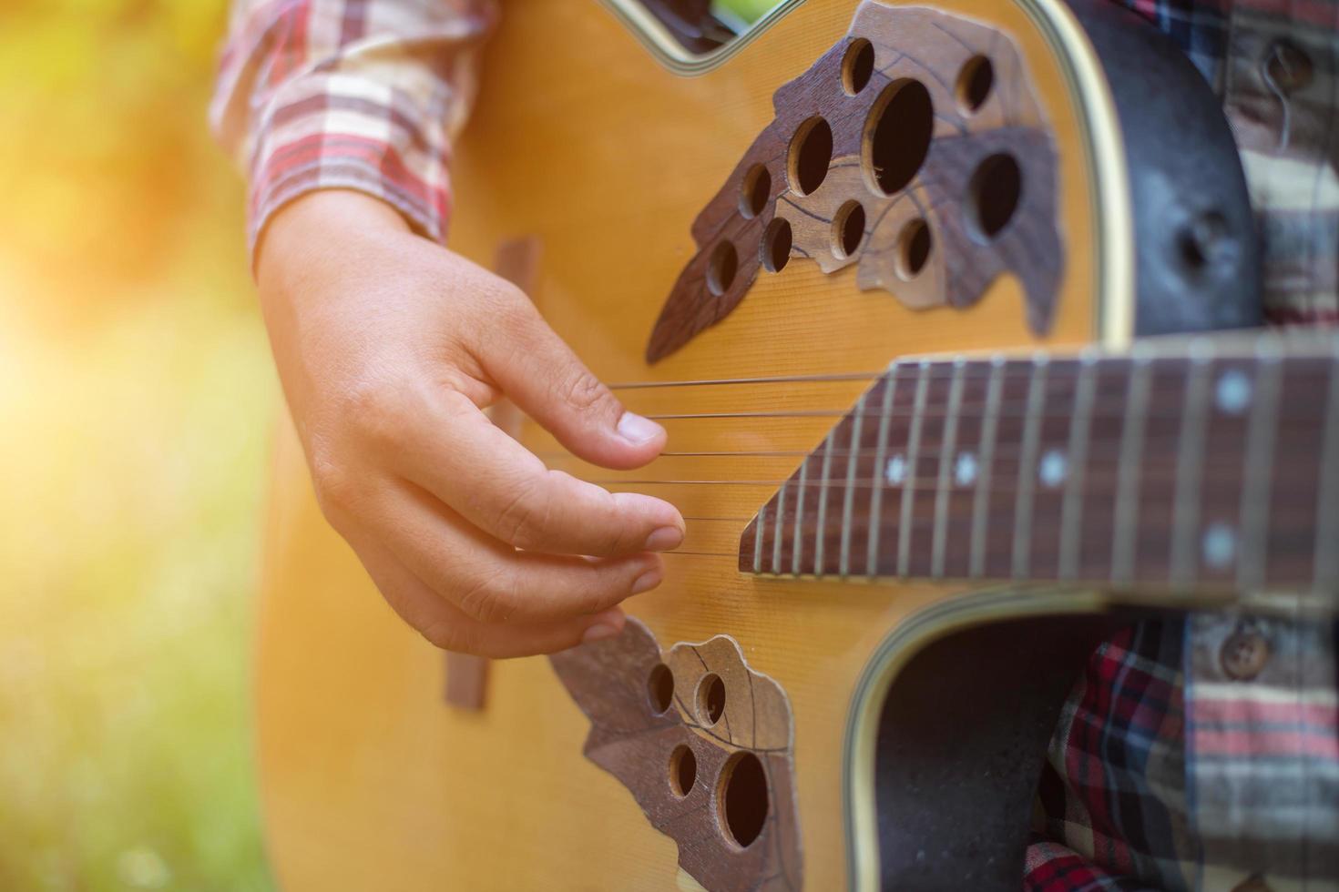 Young hipster man playing guitar to relaxing on his holiday, enjoy with natural and fresh air. photo