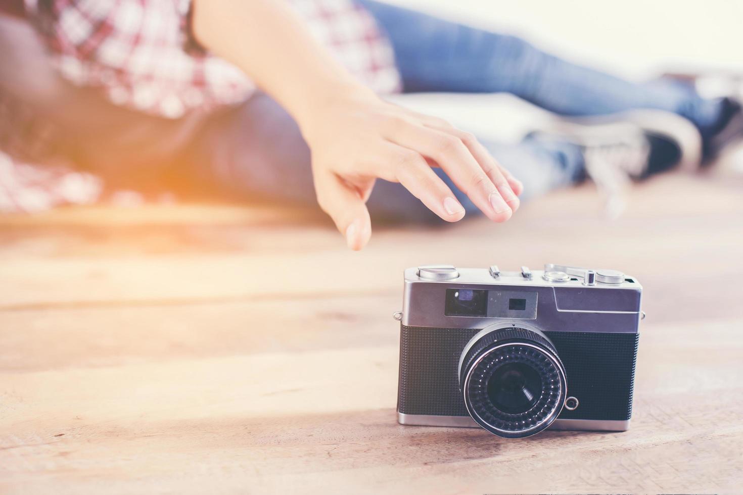 Young hipster photographer woman taking photo and look at camera sitting on wooden floor.