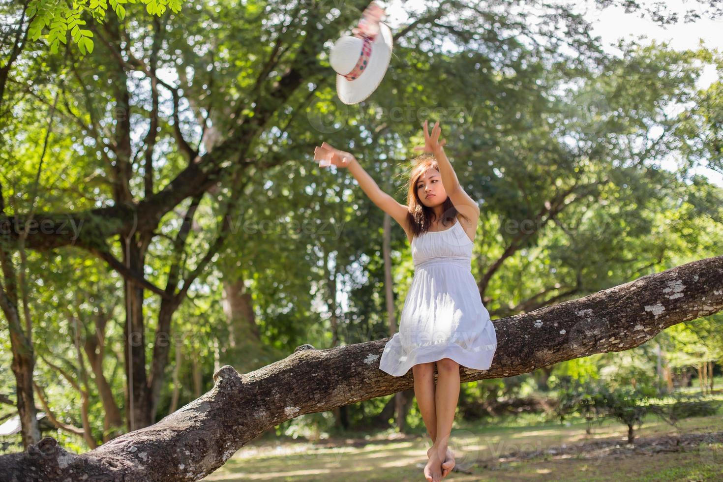 Young teen girl sitting on tree and holding balloons in hand photo