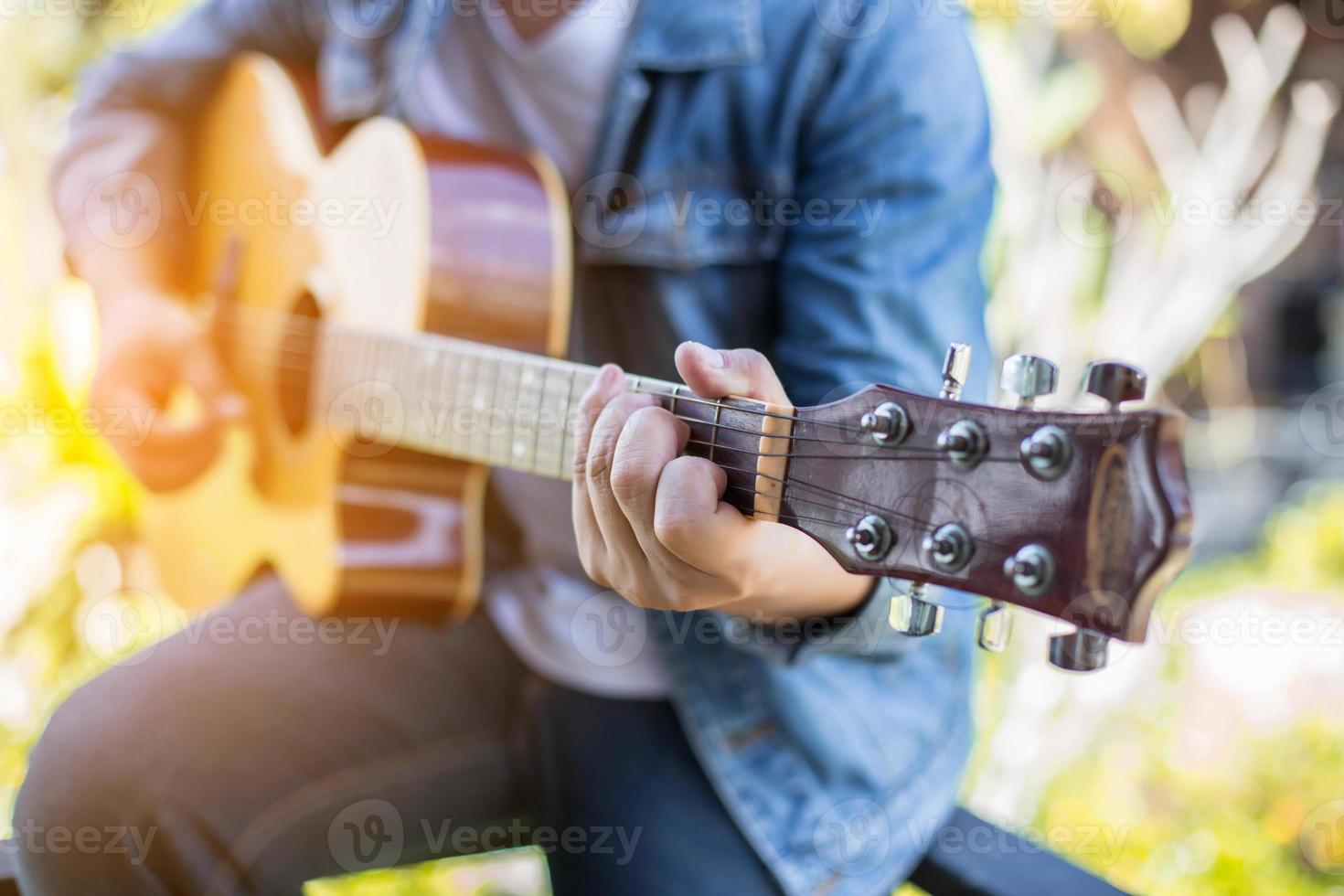 Young hipster man playing guitar to relaxing on his holiday, enjoy with natural and fresh air. photo