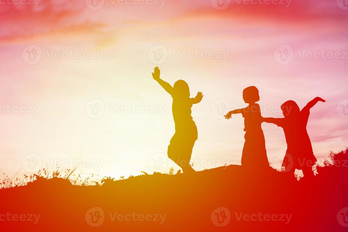 silueta de niños felices y puesta de sol feliz foto