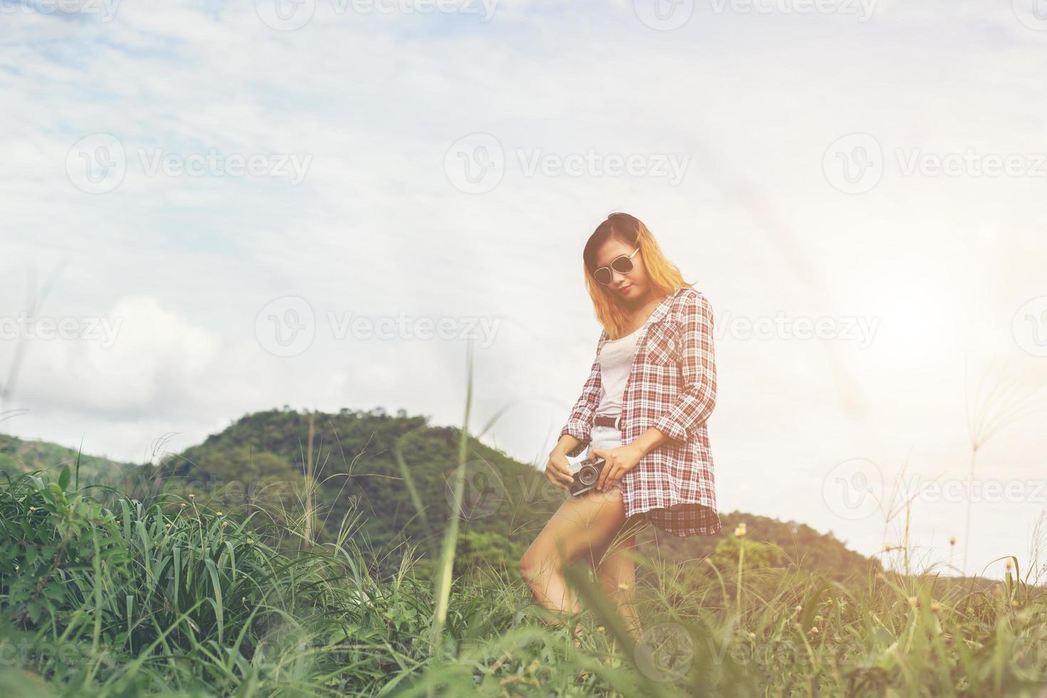 mujer joven hipster con cámara retro tomando un paisaje al aire libre, naturaleza de montaña de estilo de vida en el fondo. foto