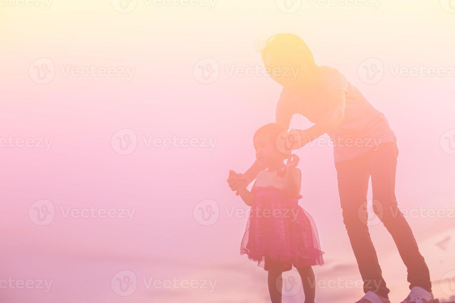 a silhouette of a happy young girl child the arms of his loving mother for a hug, in front of the sunset in the sky on a summer day. photo