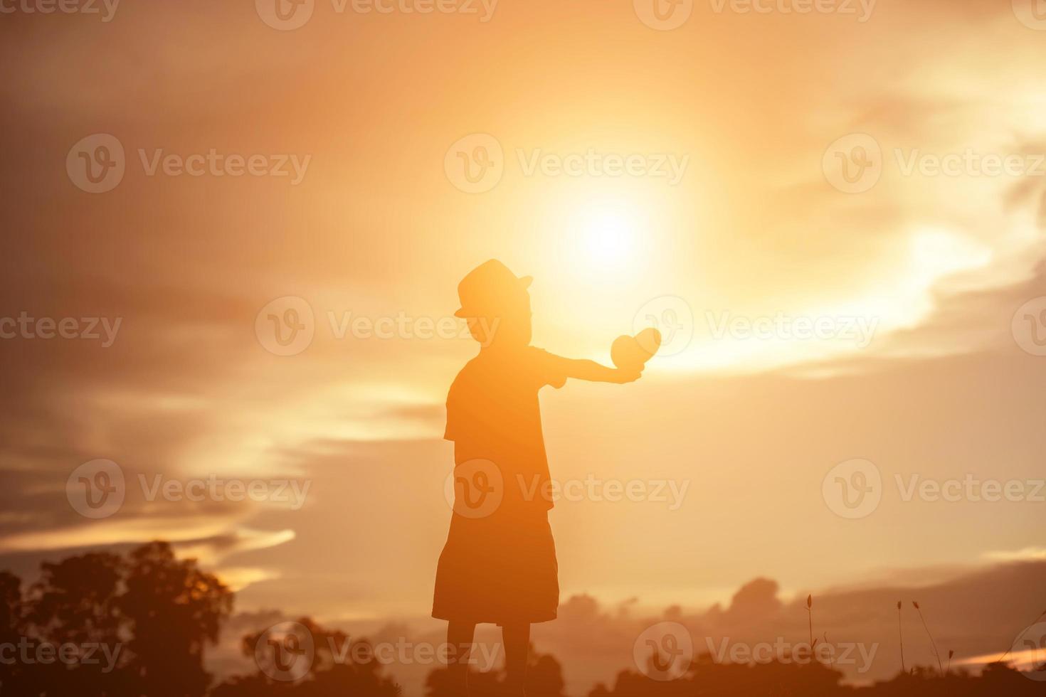 silueta de niño, momentos de alegría del niño. en la puesta de sol de la naturaleza foto