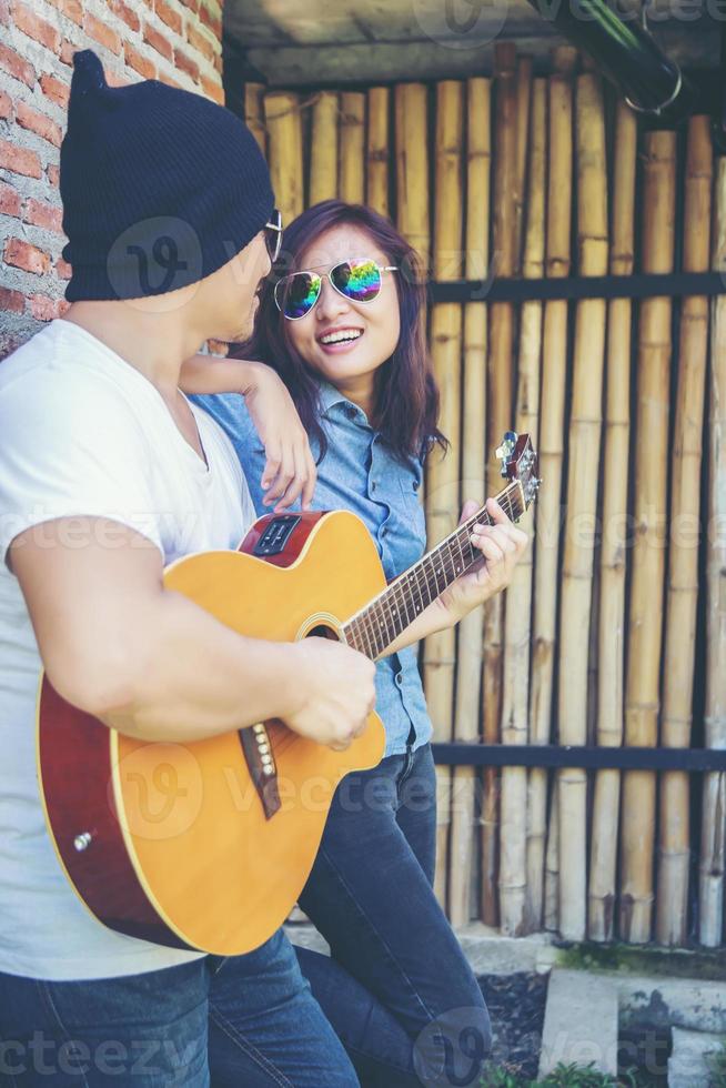 joven hipster tocando guitarra para relajarse en sus vacaciones, disfrutar con aire fresco y natural. foto