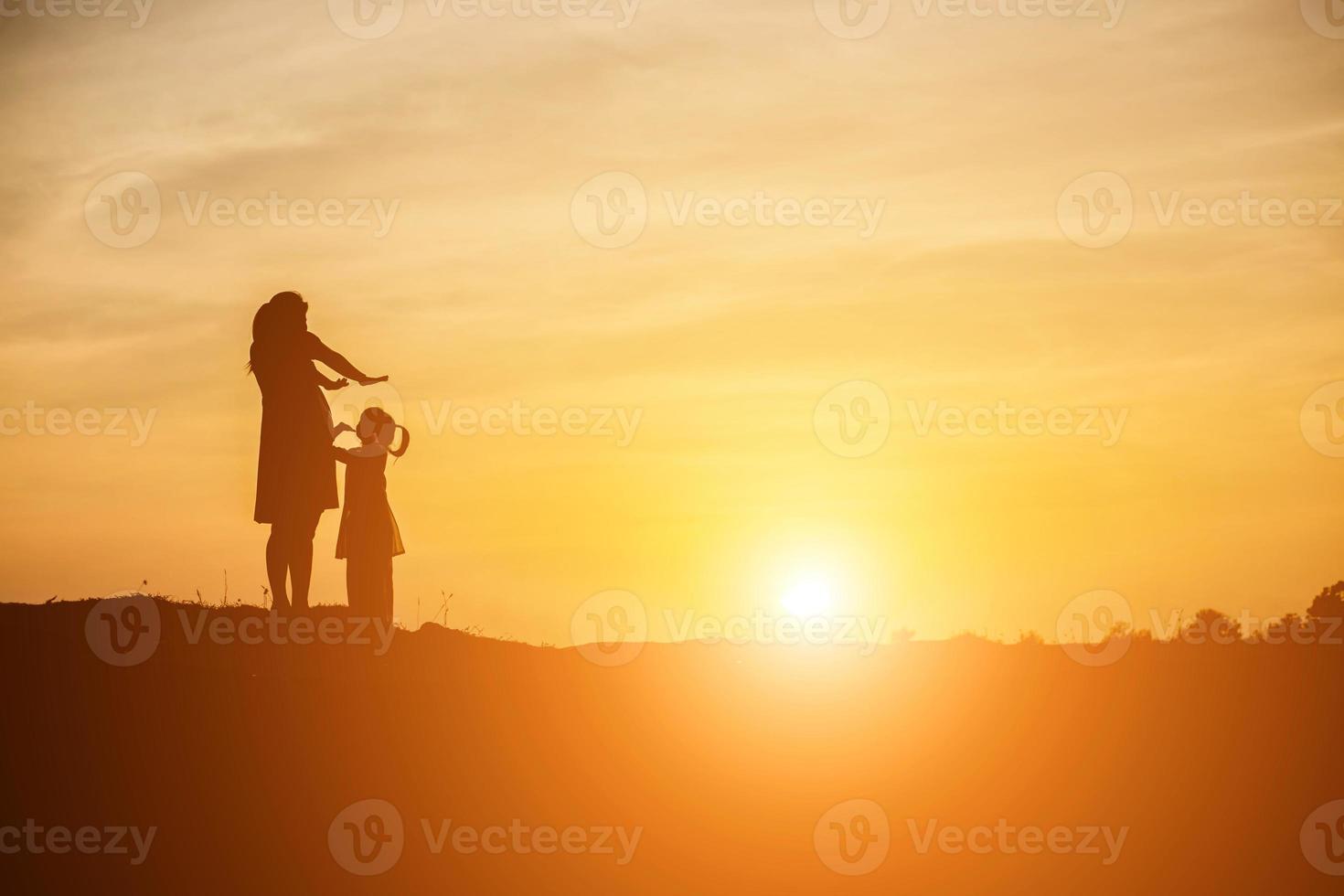 Mother encouraged her daughter out of the shadows at sunset. photo