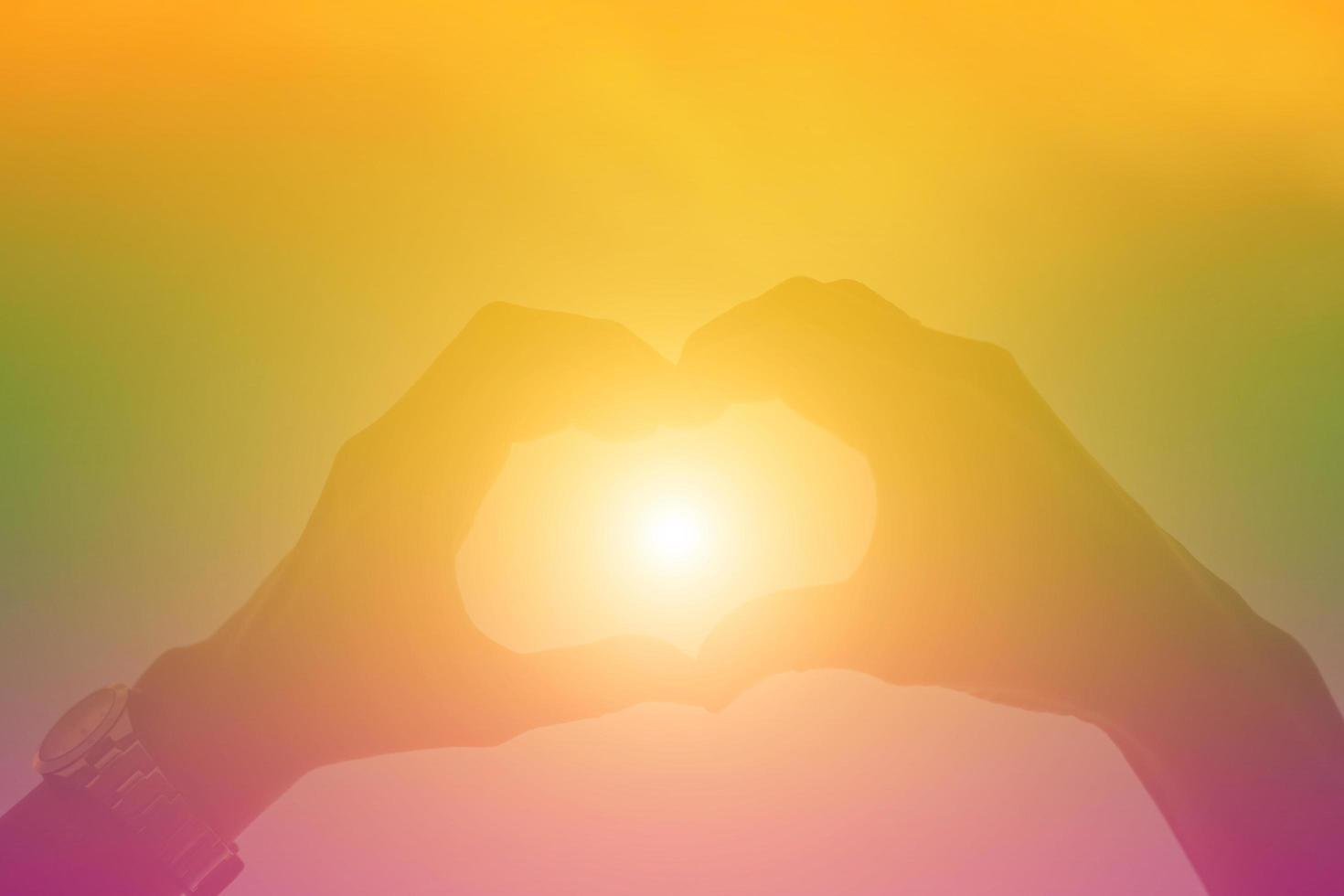 hands forming a heart shape with sunset silhouette photo