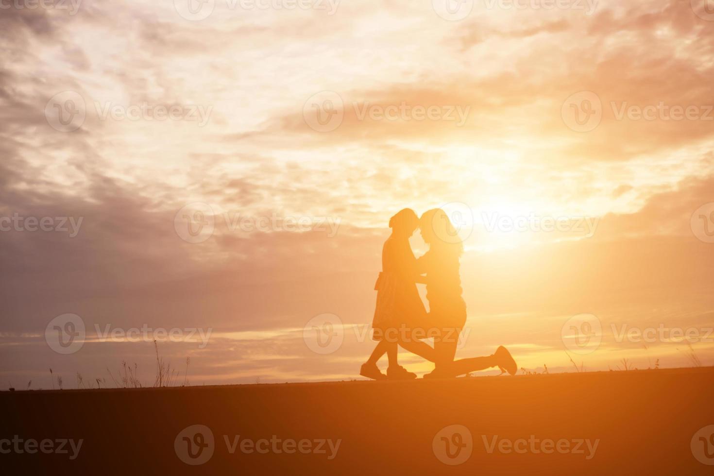 a silhouette of a happy young girl child the arms of his loving mother for a hug, in front of the sunset in the sky on a summer day. photo