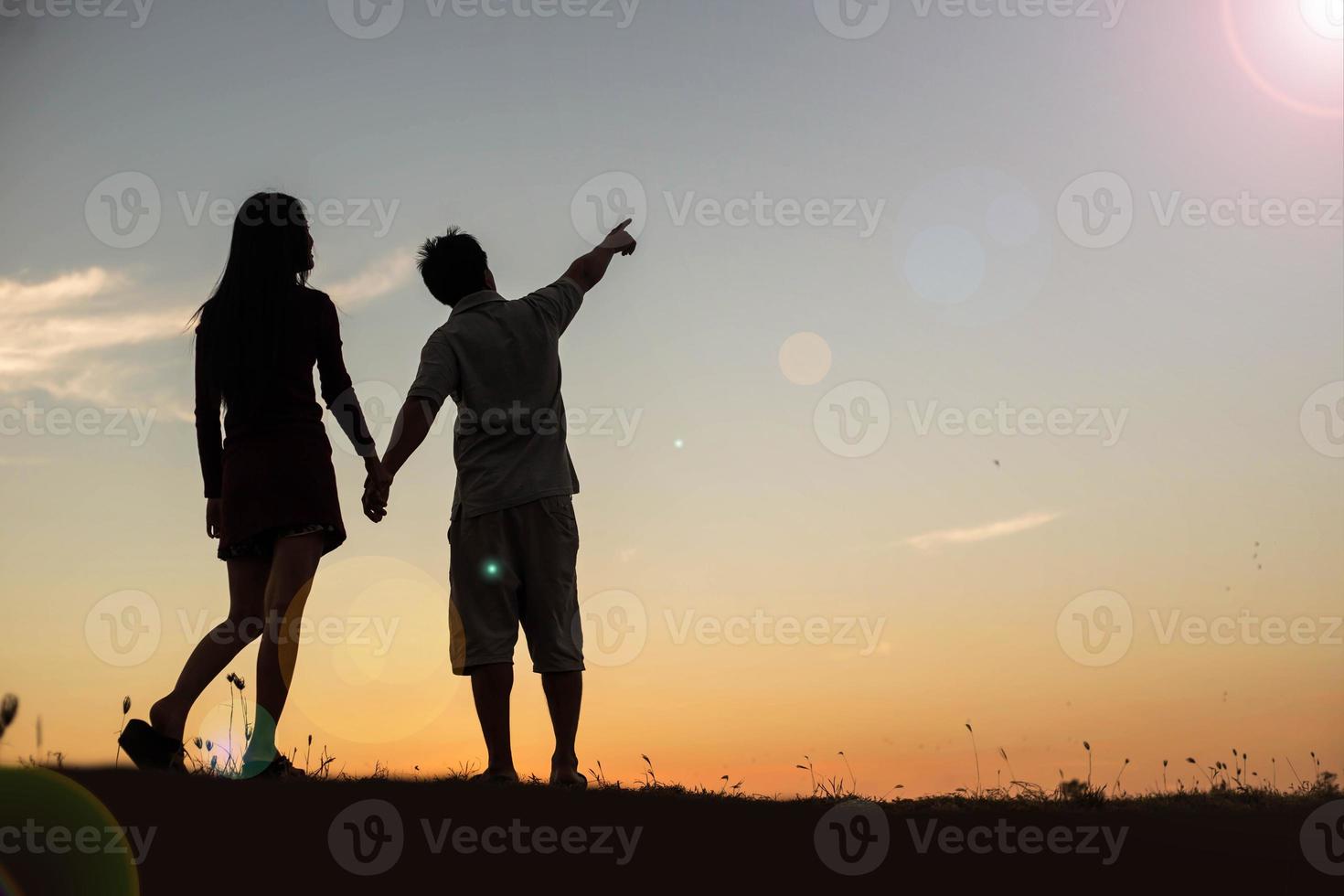 silhouette of a man and woman holding hands with each other, walking together. photo