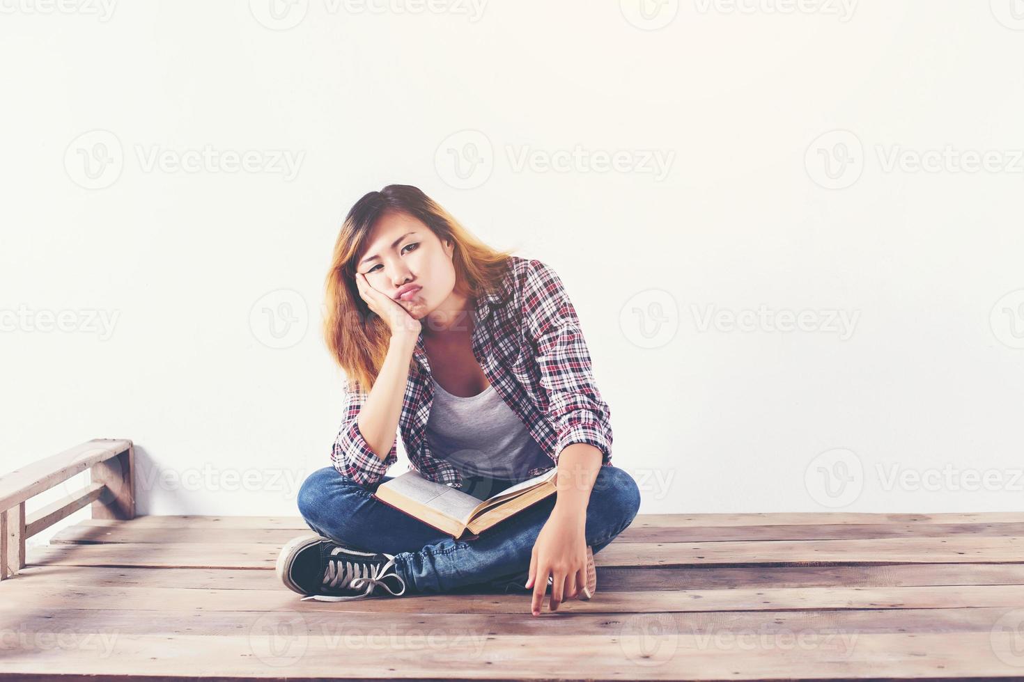 Young hipster woman holding books and pointing up on isolated white background. photo
