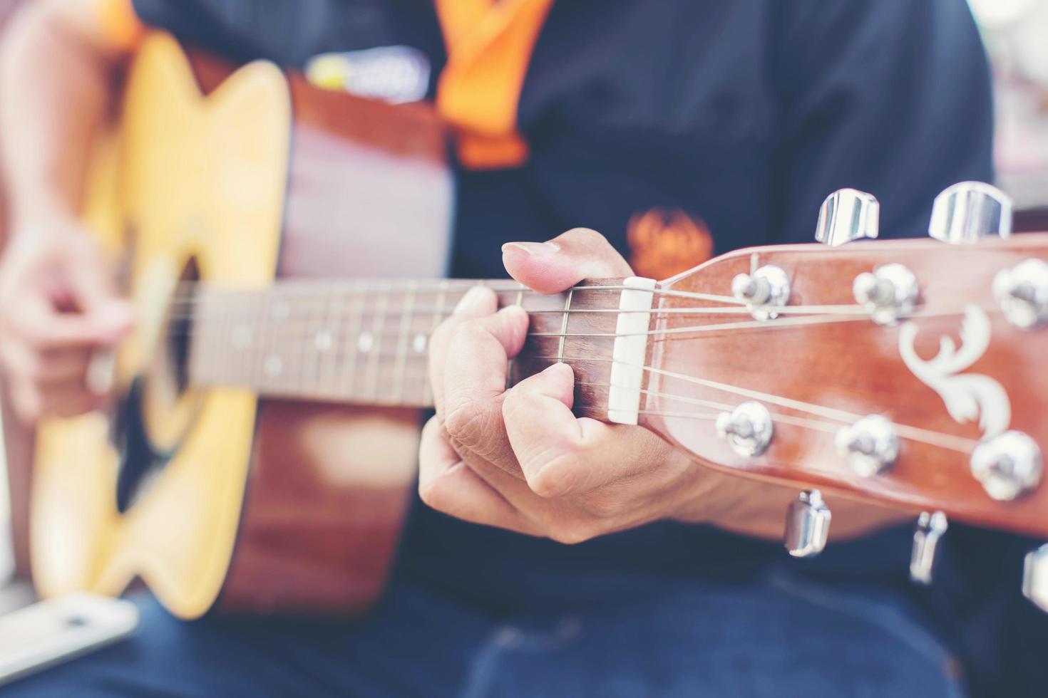 Cerca de la mano del hombre tocando la guitarra foto