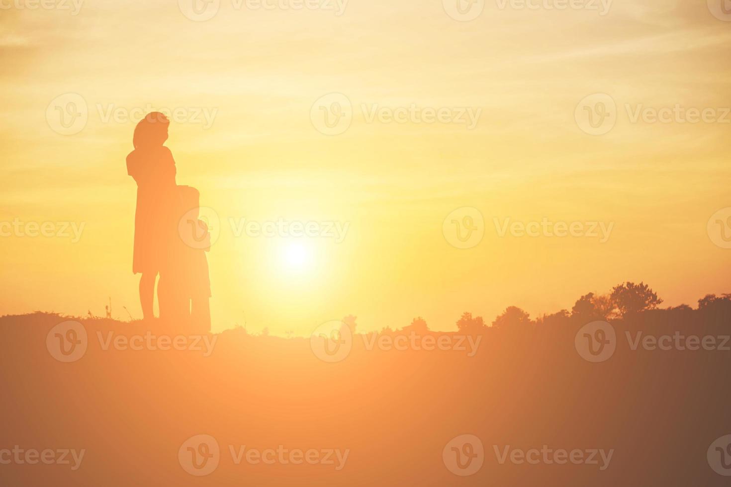 Mother encouraged her daughter out of the shadows at sunset. photo