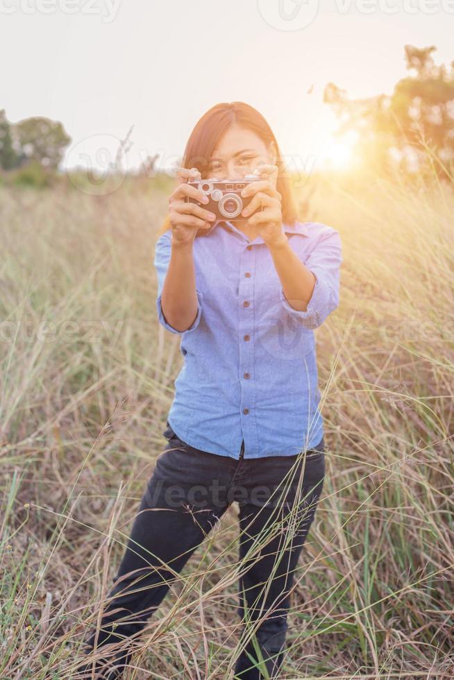 vintage de fotografía de mujeres hermosas mano de pie sosteniendo cámara retro con amanecer, estilo suave de ensueño foto