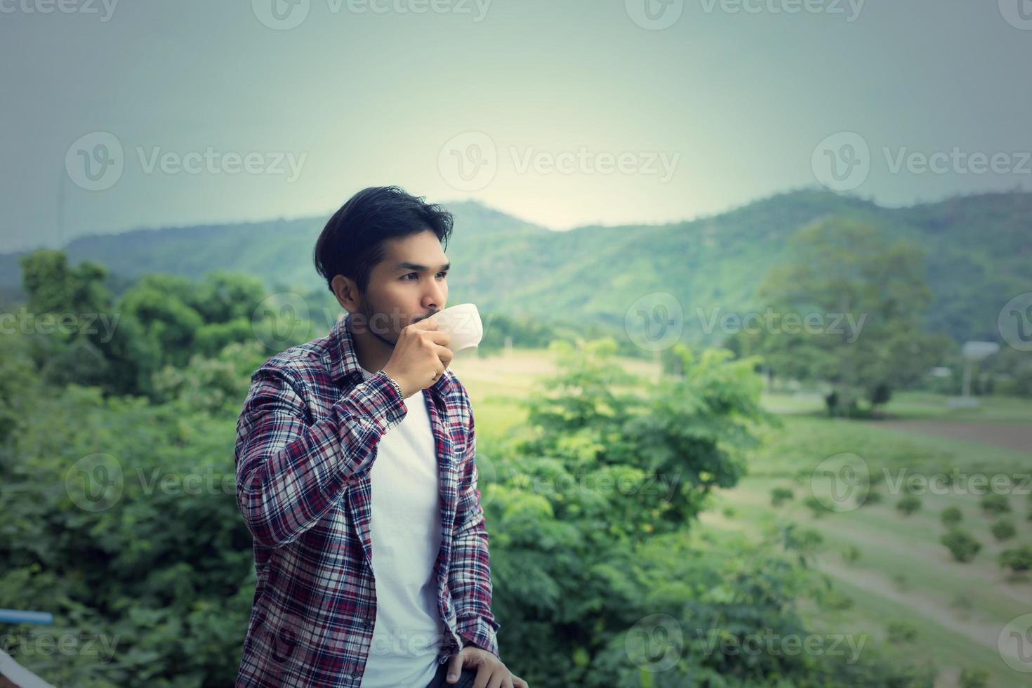 apuesto hombre barbudo hipster con una taza de café matutino caminando en el parque. foto