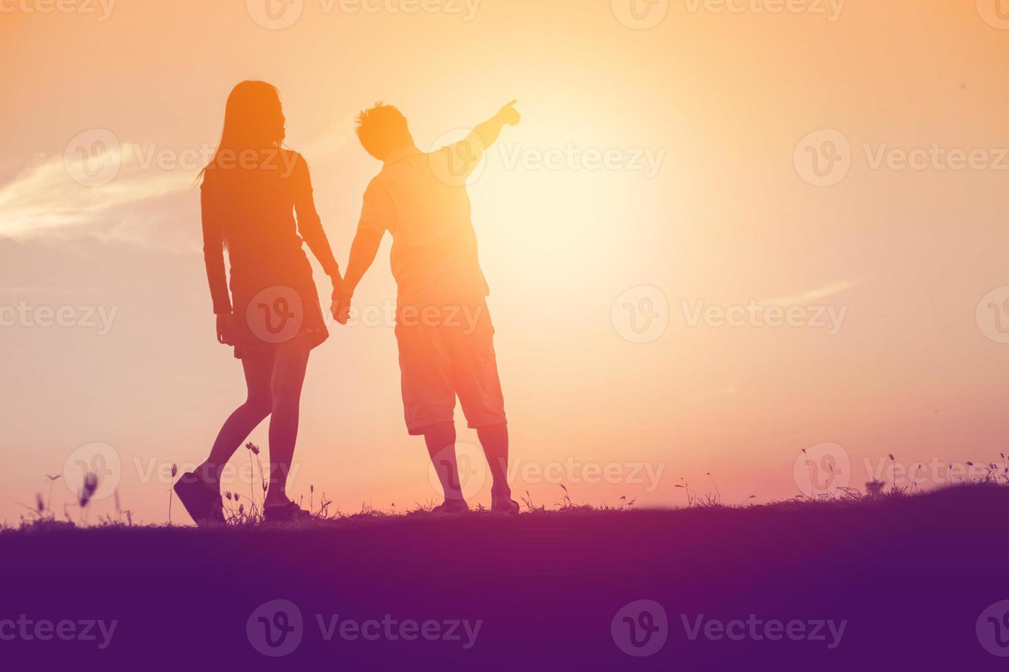 silhouette of a man and woman holding hands with each other, walking together. photo