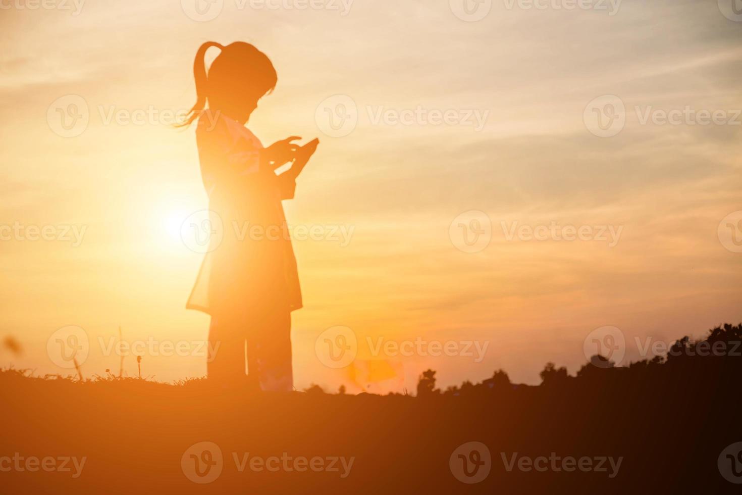 silueta de niño, momentos de alegría del niño. en la puesta de sol de la naturaleza foto