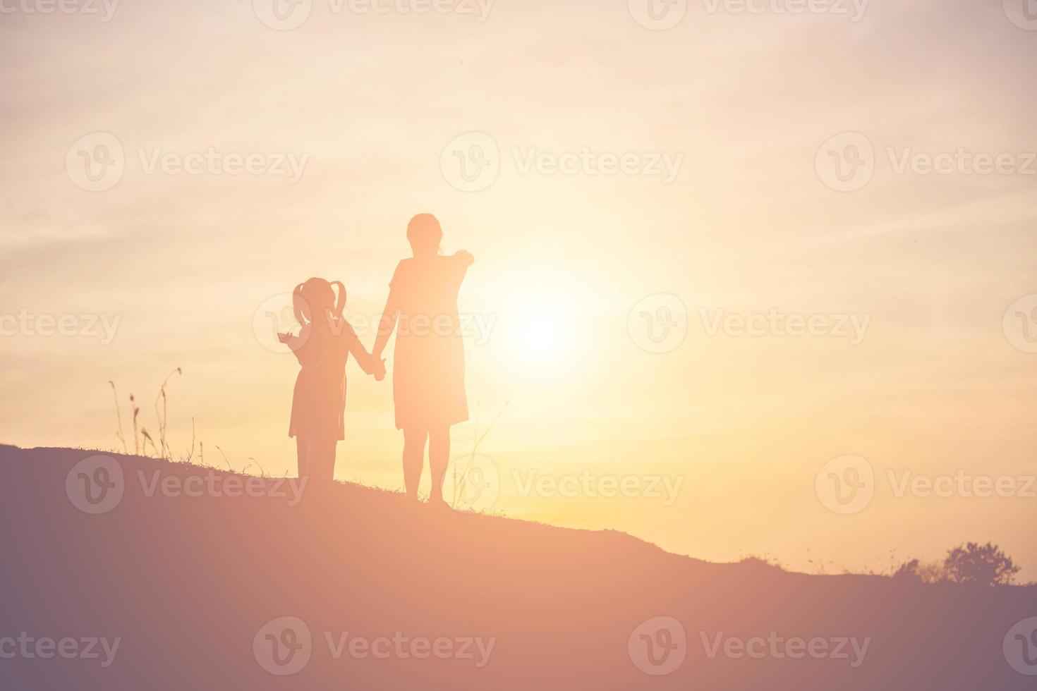 Mother encouraged her daughter out of the shadows at sunset. photo