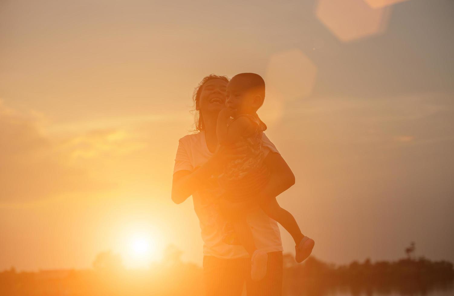 Silhouettes of mother and little daughter walking at sunset photo
