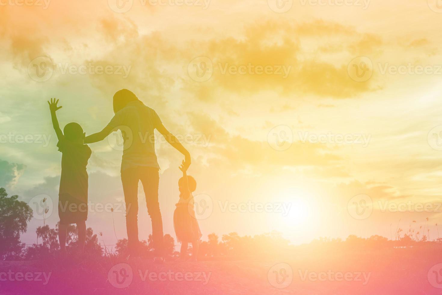 a silhouette of a happy young girl child the arms of his loving mother for a hug, in front of the sunset in the sky on a summer day. photo