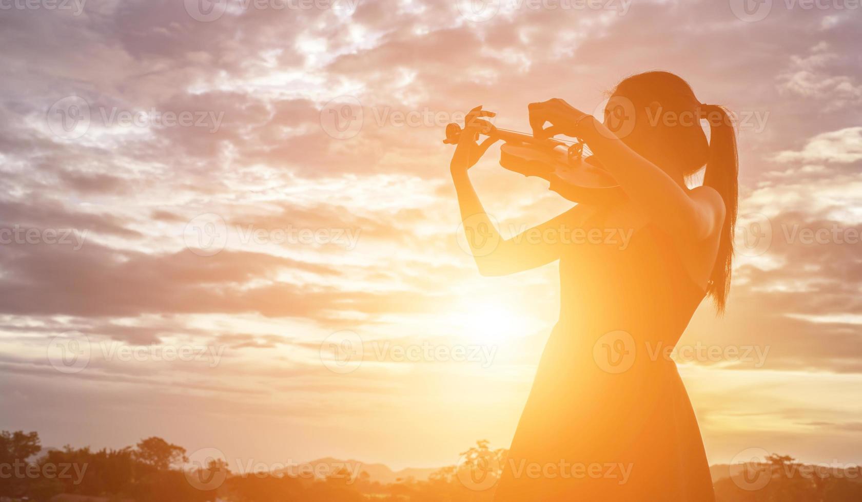 Young woman playing the violin With mountains in the background photo