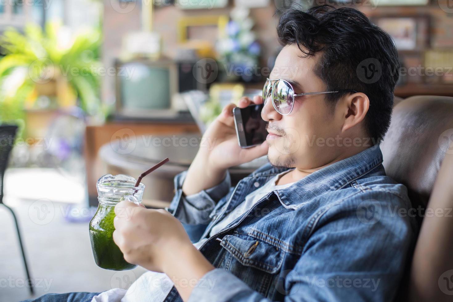 Young man with smartphone smiling relaxing at cafe. photo