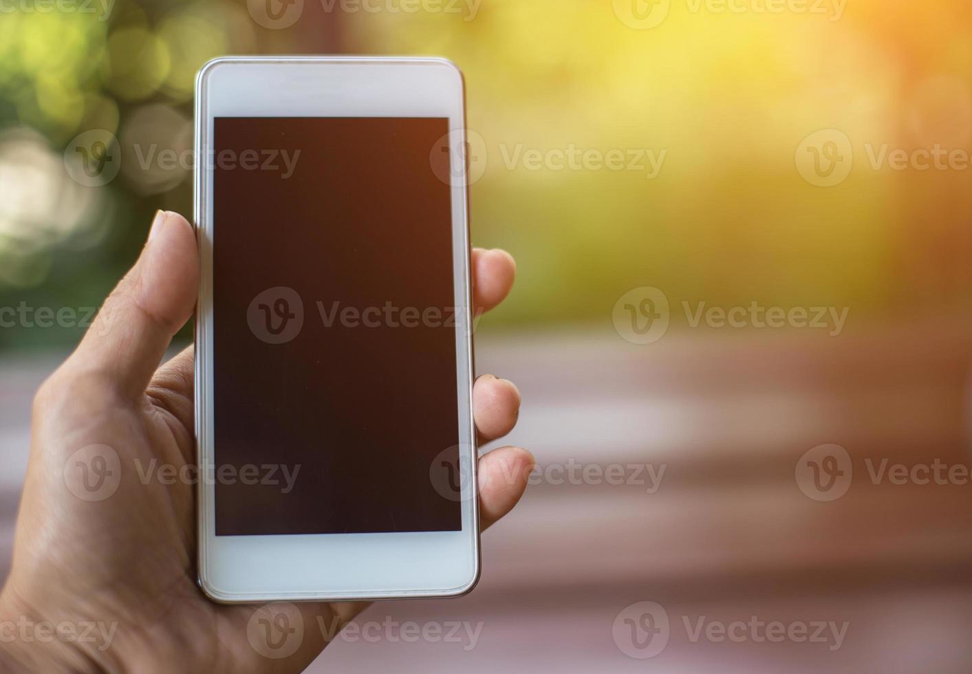 Hand holding white mobile phone on vintage weave wood table photo