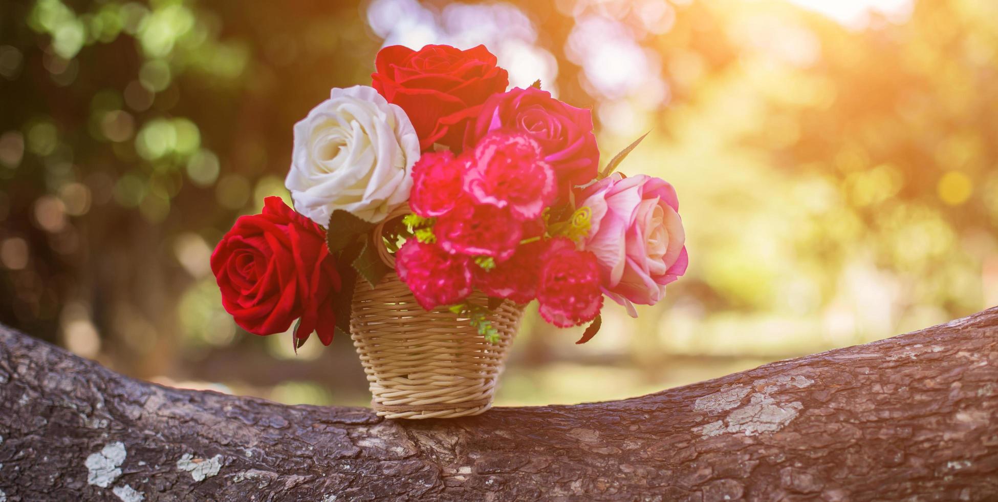 Mixed beautiful flowers in the vase on wooden background photo