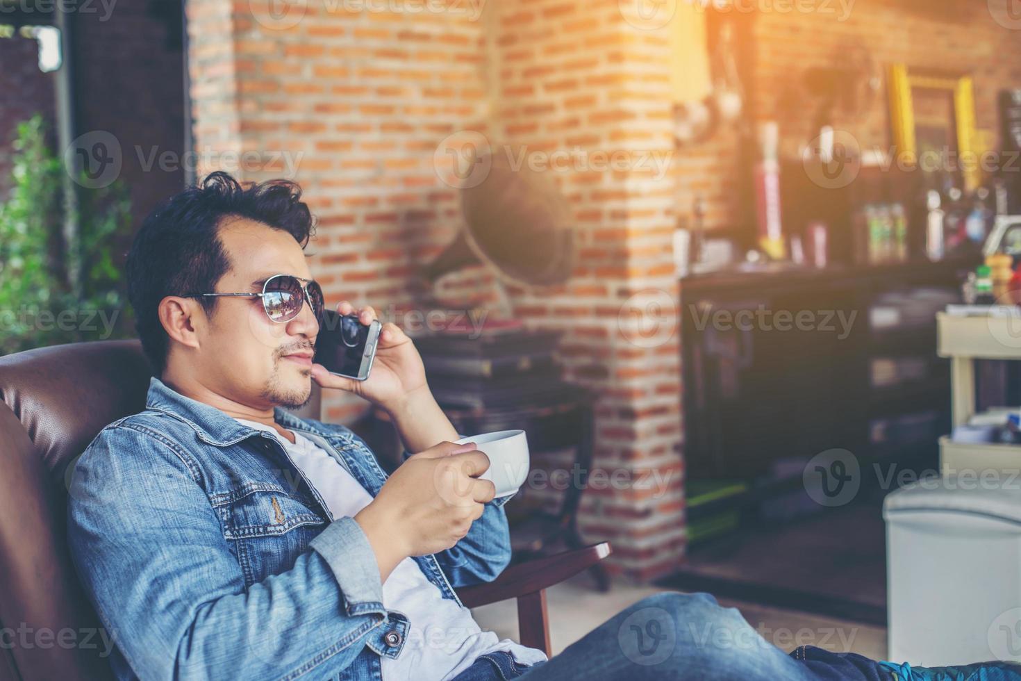 Young man with smartphone smiling relaxing at cafe. photo