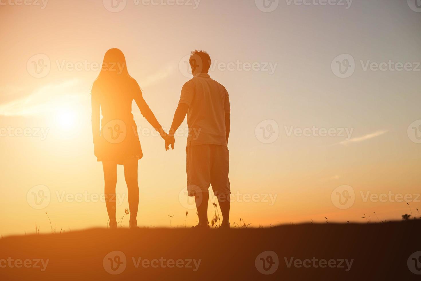 silhouette of a man and woman holding hands with each other, walking together. photo