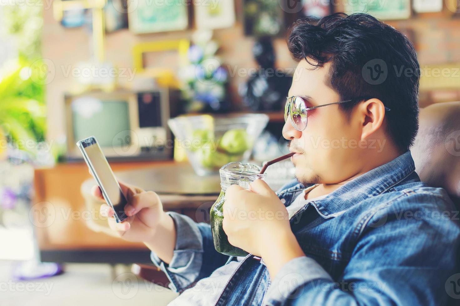 Young man with smartphone smiling relaxing at cafe. photo