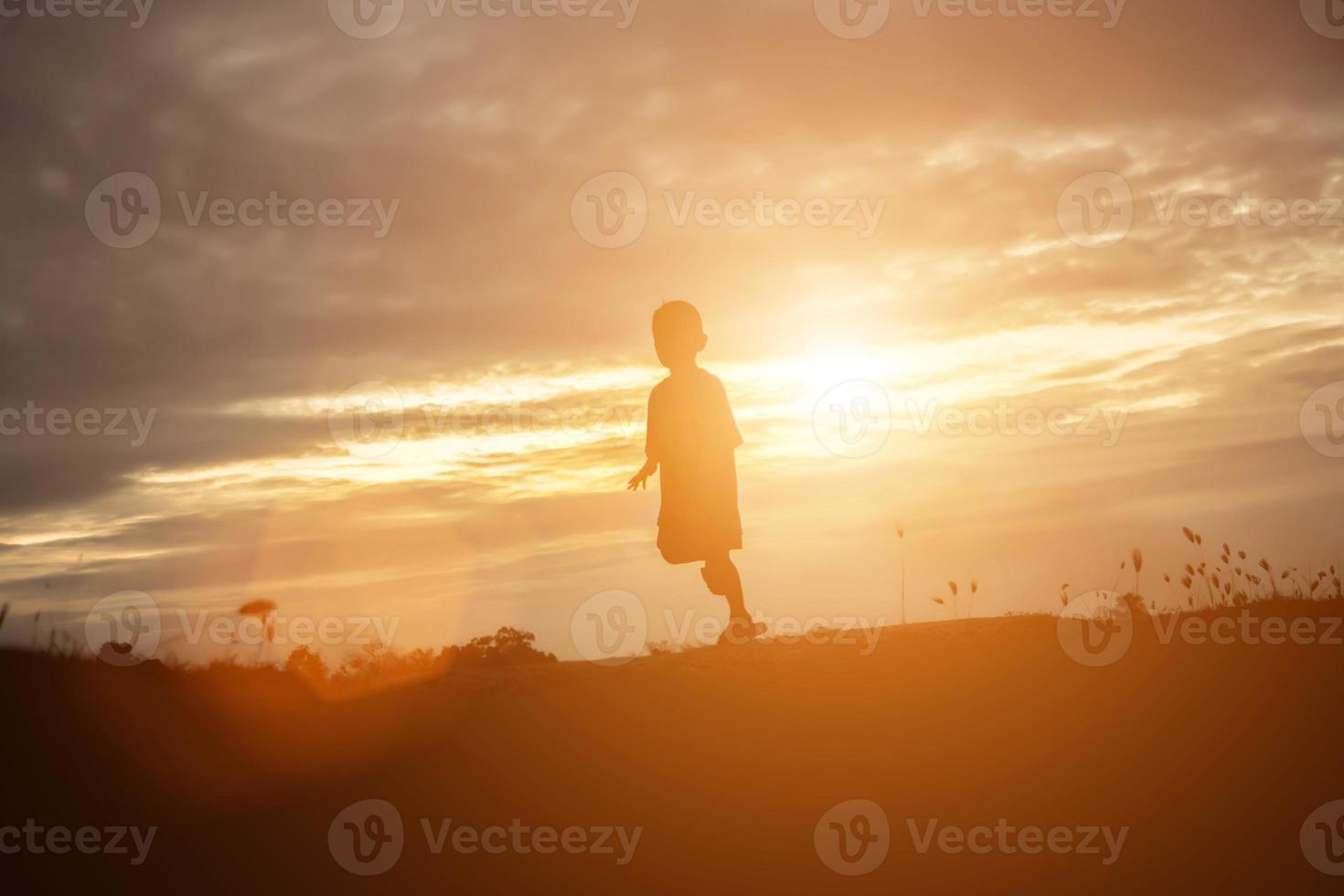 silueta de niño, momentos de alegría del niño. en la puesta de sol de la naturaleza foto