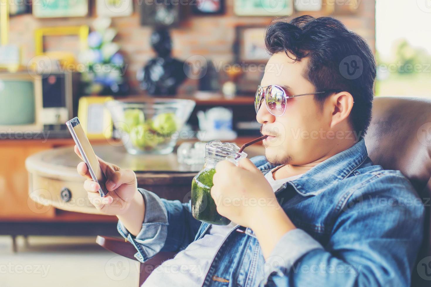 Young man with smartphone smiling relaxing at cafe. photo