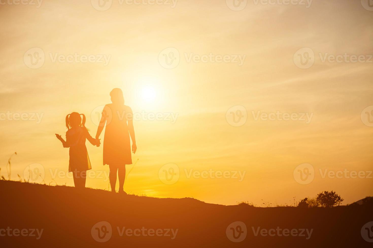 Mother encouraged her daughter out of the shadows at sunset. photo