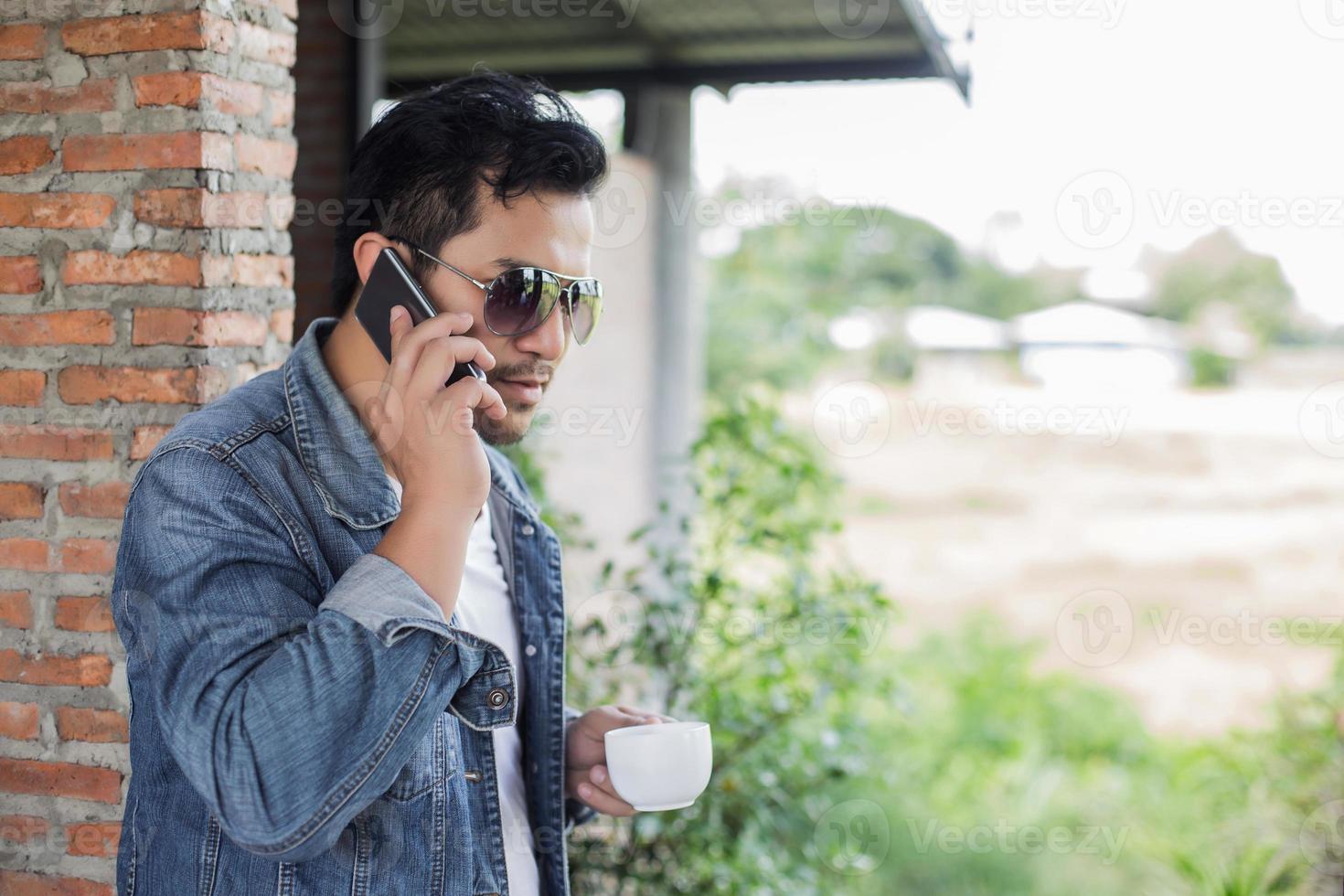 Young man with smartphone smiling relaxing at cafe. photo