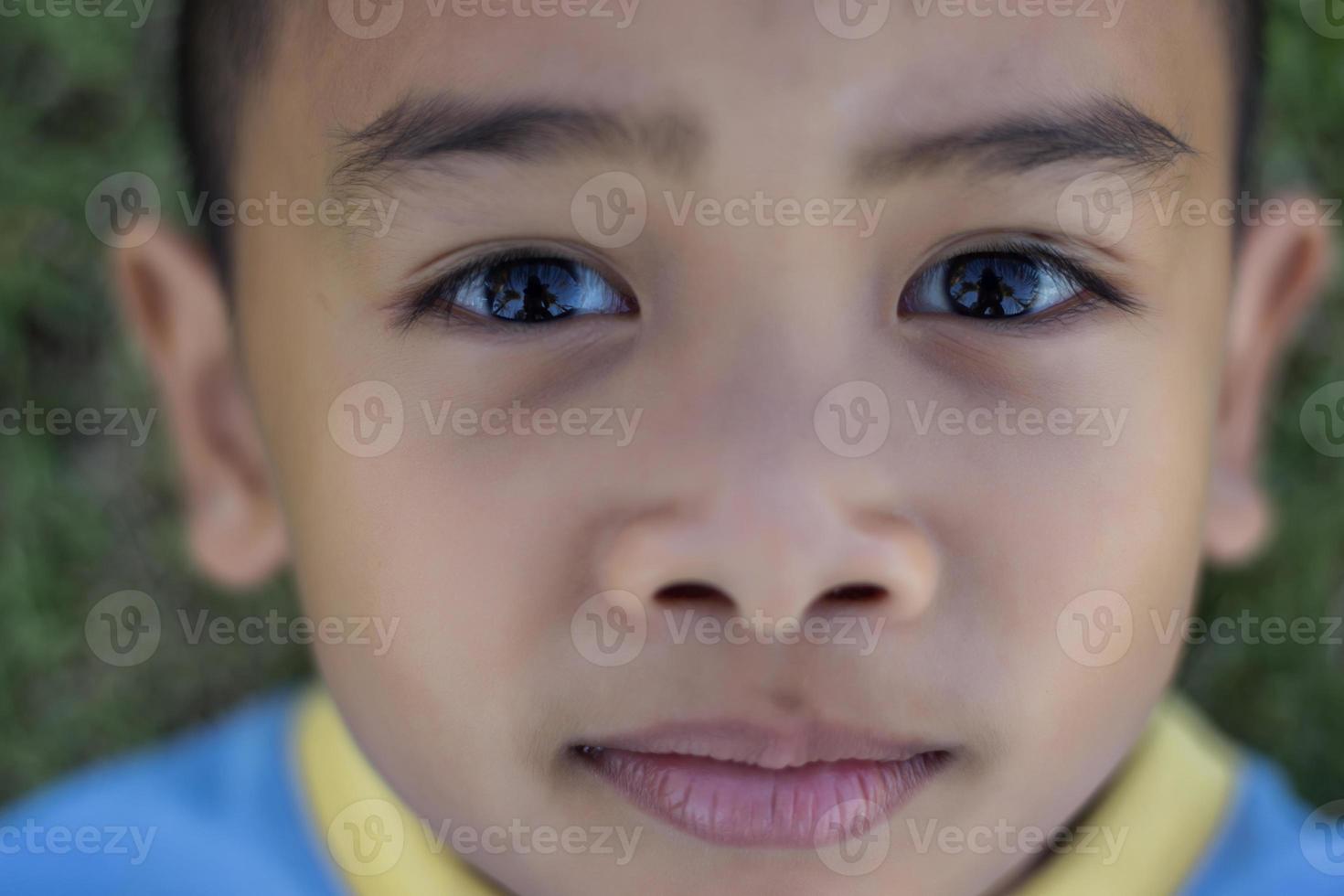 Happy boy child is smiling enjoying adopted life. Portrait of young boy in nature, park or outdoors. Concept of happy family or successful adoption or parenting. photo