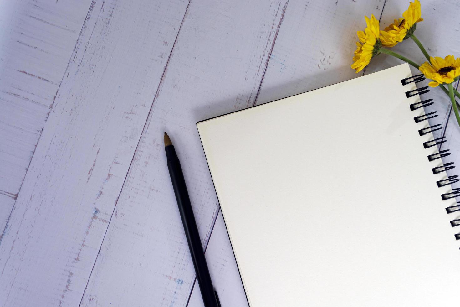 Note book flat lay with sunflowers on wooden desk. Directly above. photo