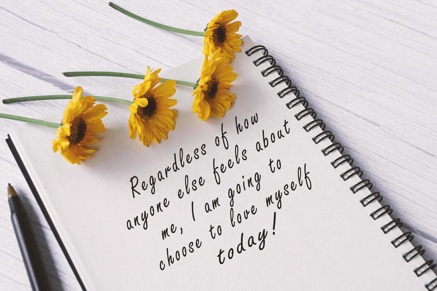 Motivational quote on note book with sunflowers on wooden desk. photo