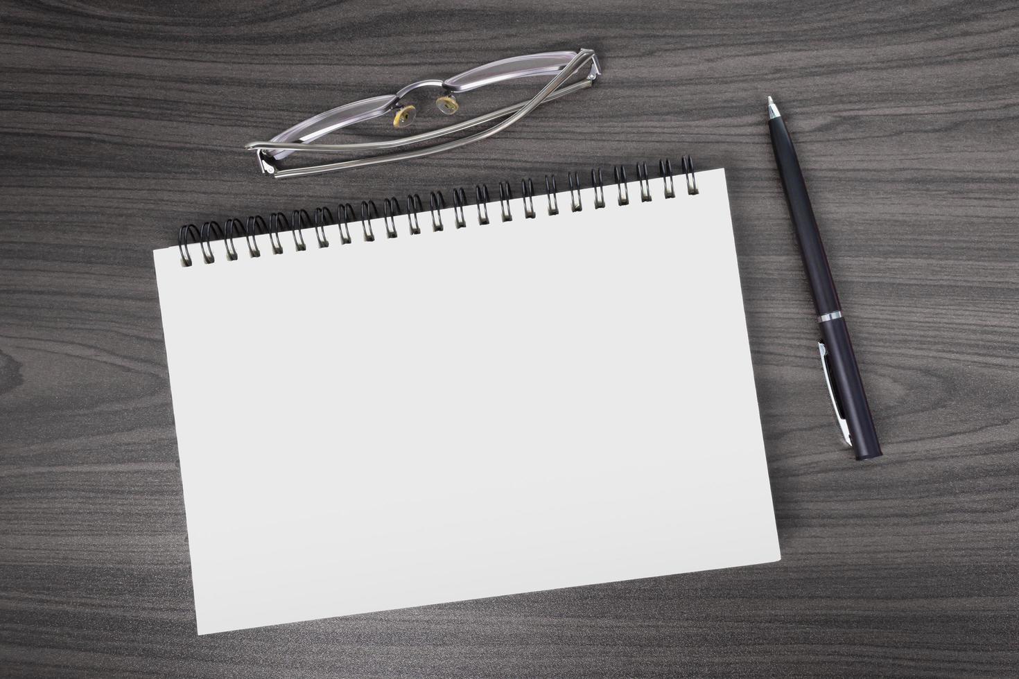 Directly above view of office wooden table with pen, notepad and reading glasses photo