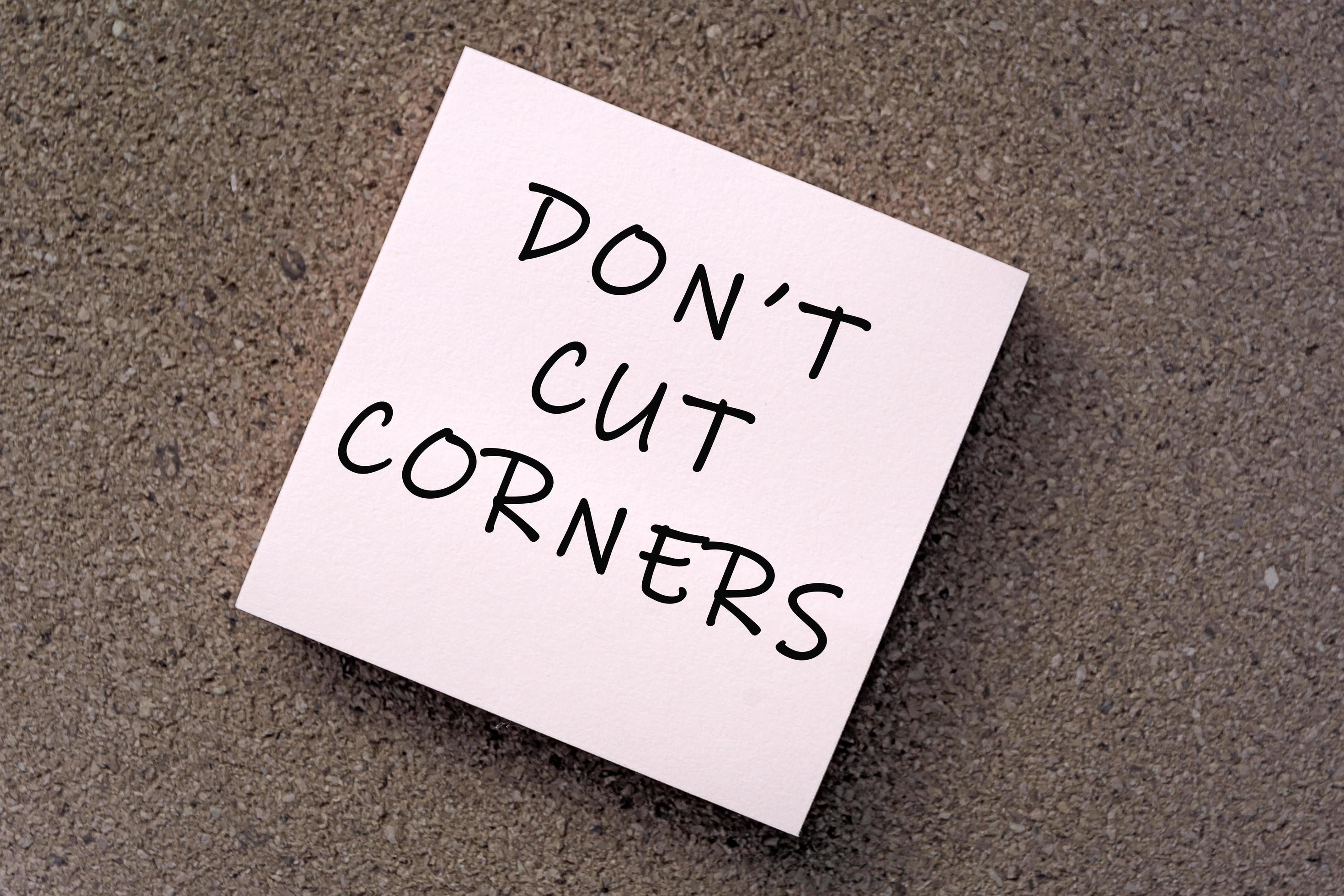 Don't cut corners message on sticky note against brown paper. 7967680