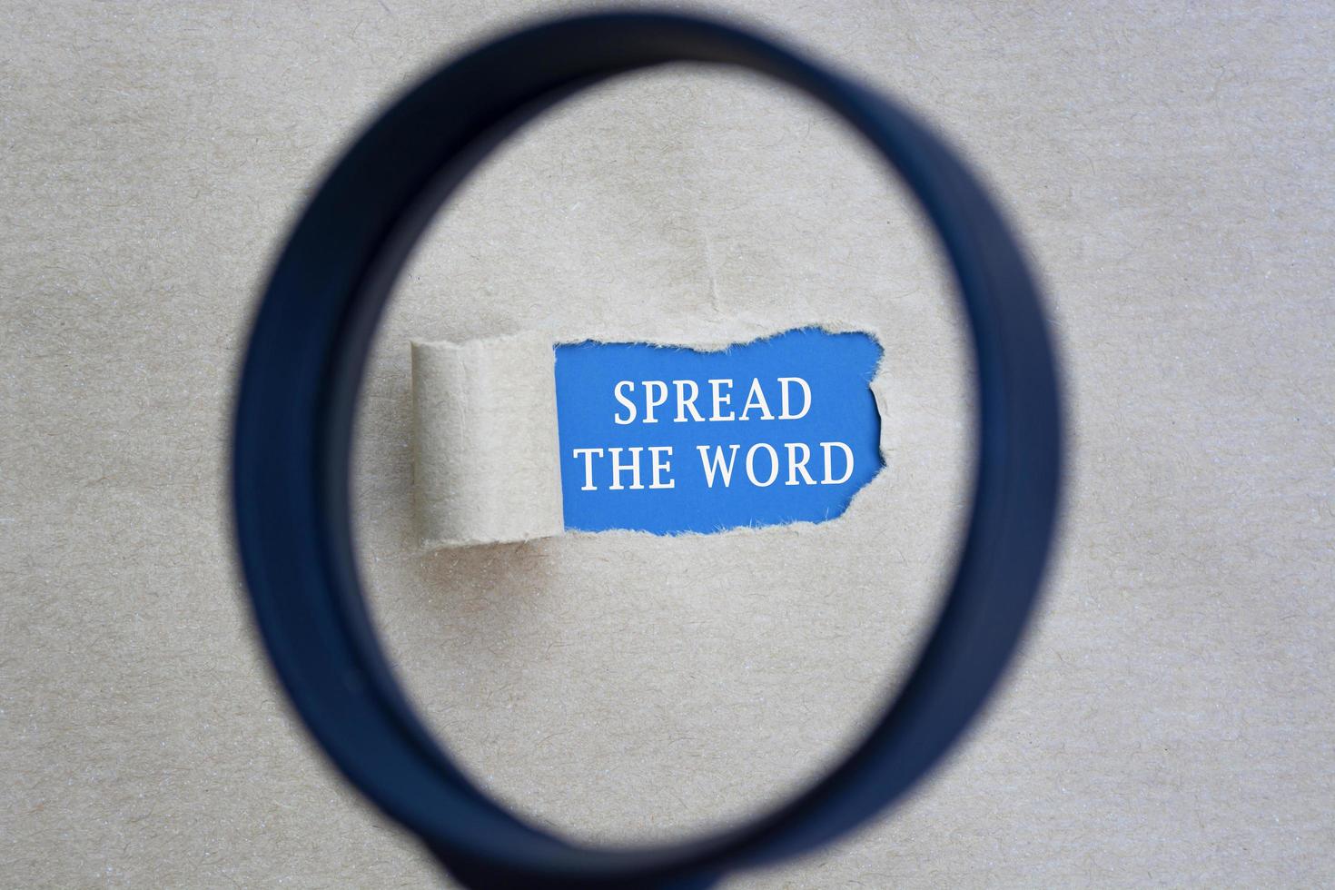 Spread the word text on torn paper with magnifying glass. Network concept. photo