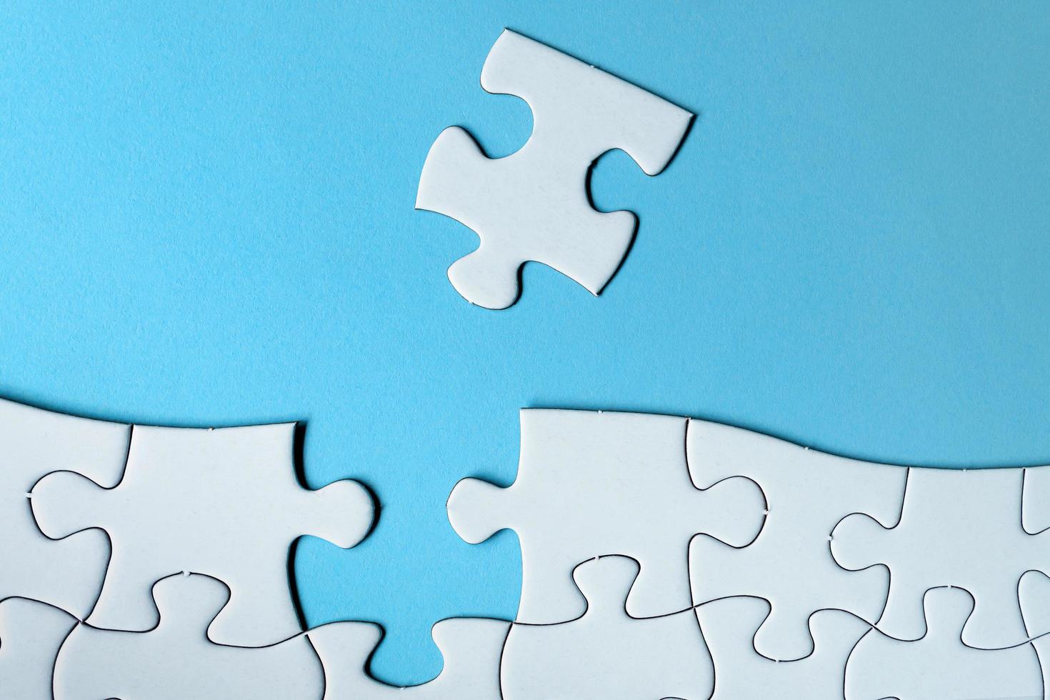 Piece of jigsaw puzzle on blue paper. Directly above. Copy space. photo